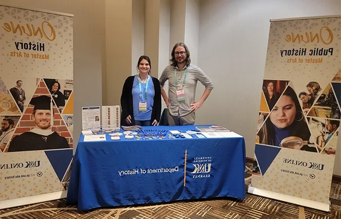 a student and professor man a booth at a conference