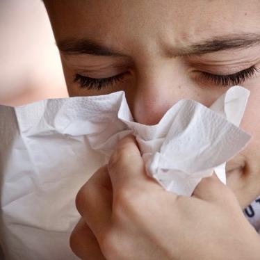 person sneezing with tissue on nose